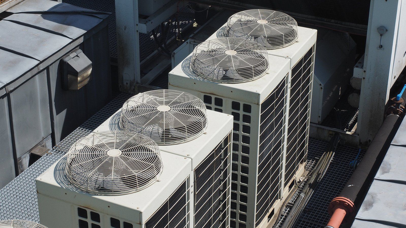 Air conditioning units on a building rooftop, with fan blades visible.