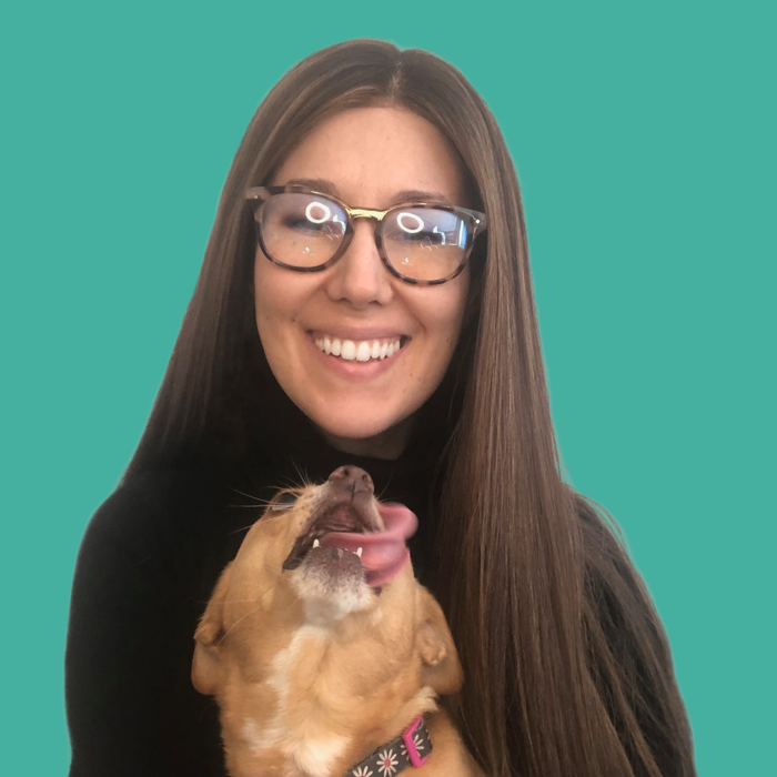 A woman wearing glasses is holding a dog with its tongue out.