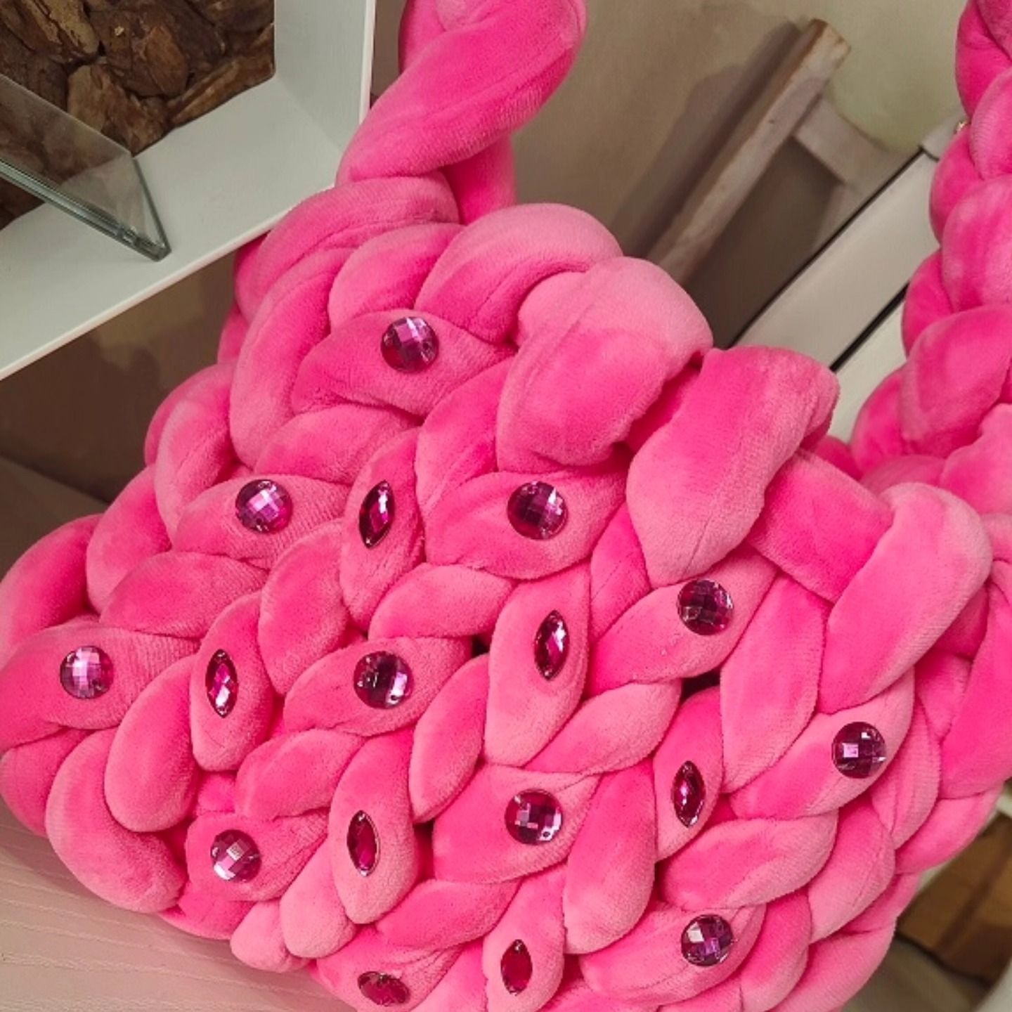 Una borsa a mano rosa acceso, in maglia grossa, decorata con strass rosa sparsi, rotondi e a forma di marquise.