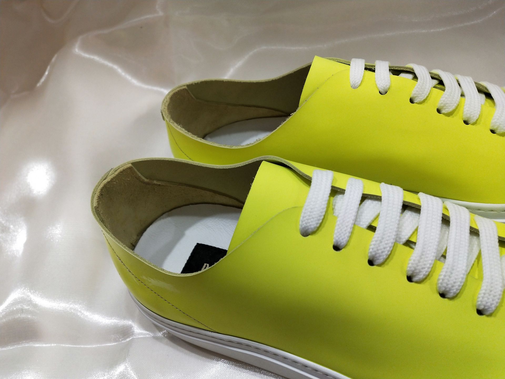 Un paio di scarpe da ginnastica giallo neon acceso con lacci bianchi, viste da un'angolazione dall'alto e in primo piano.