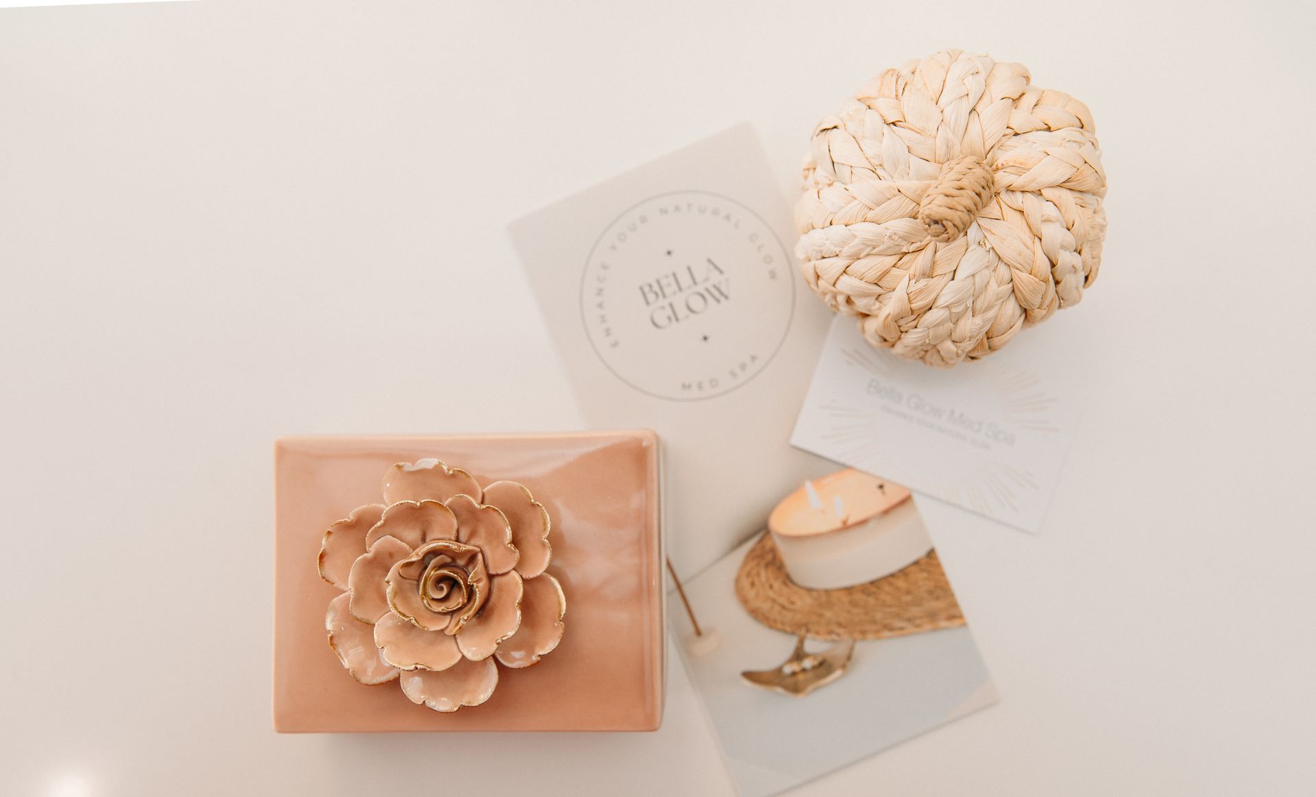 A white pumpkin is sitting on a table next to a flower and a card.