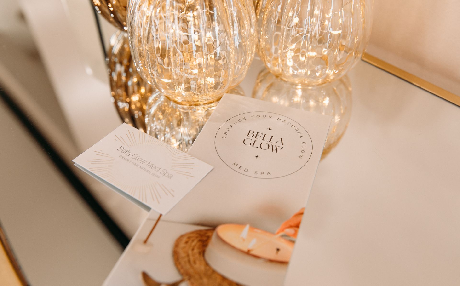 A book is sitting on a table next to a candle and glasses.