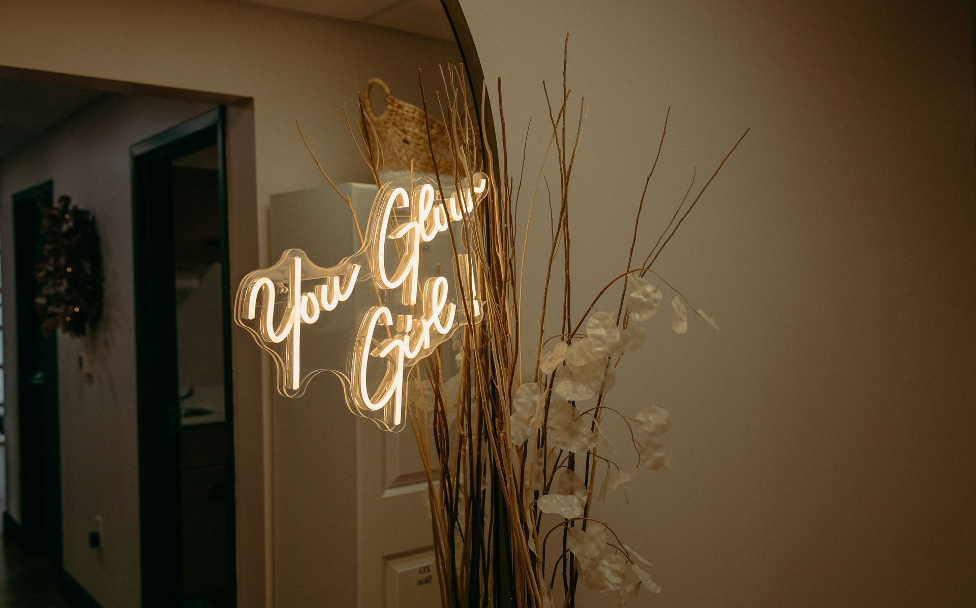 A neon sign that says `` you glow girl '' is hanging on a wall.