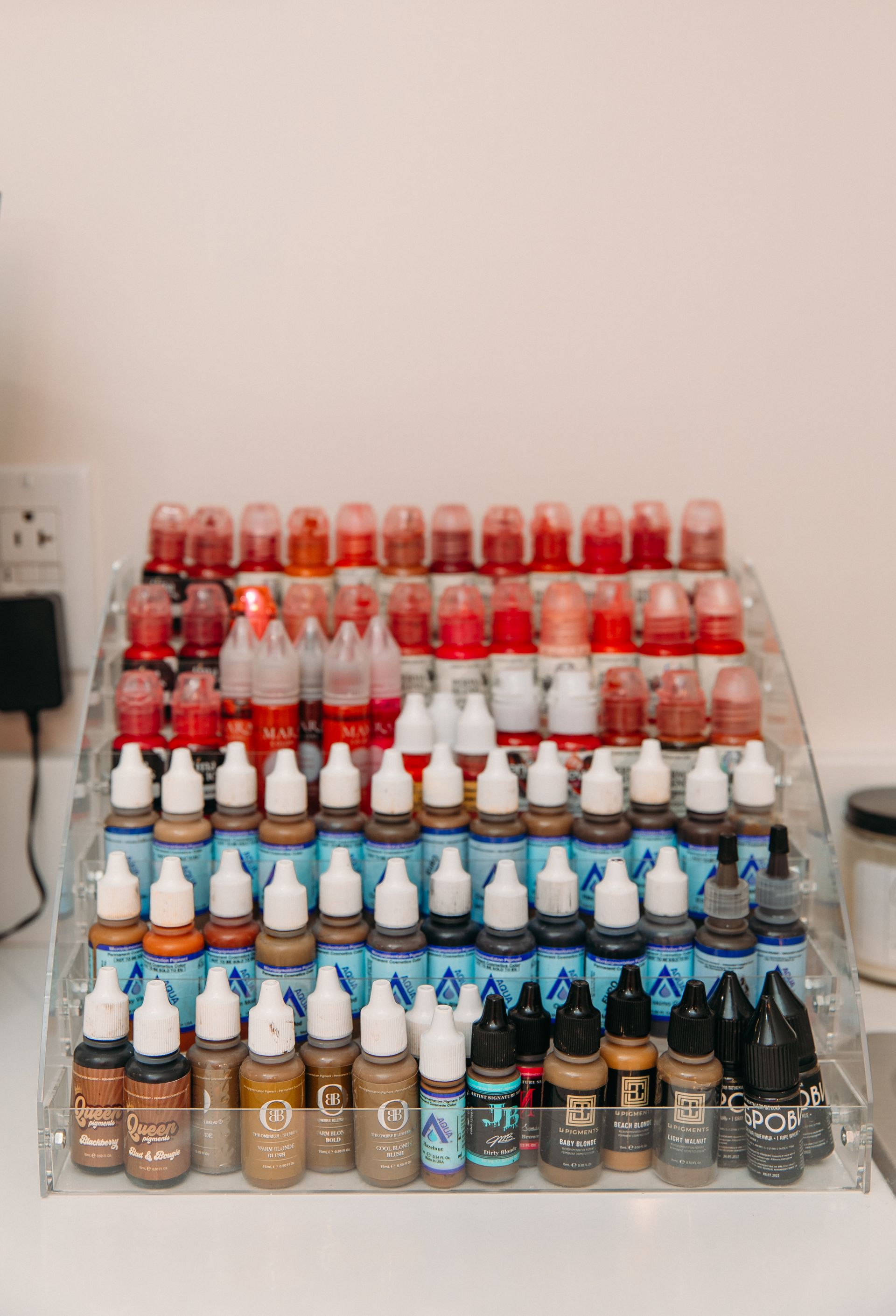 A shelf filled with lots of bottles of makeup on a table.