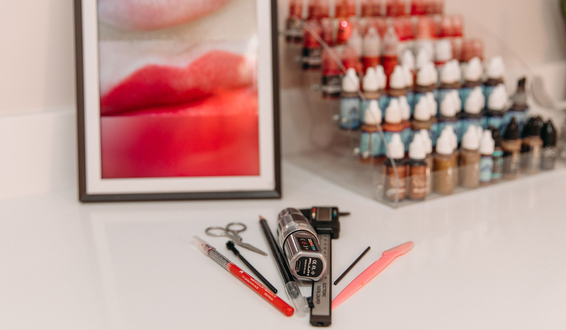 A picture of a woman 's lips is sitting on a table next to a tattoo machine.