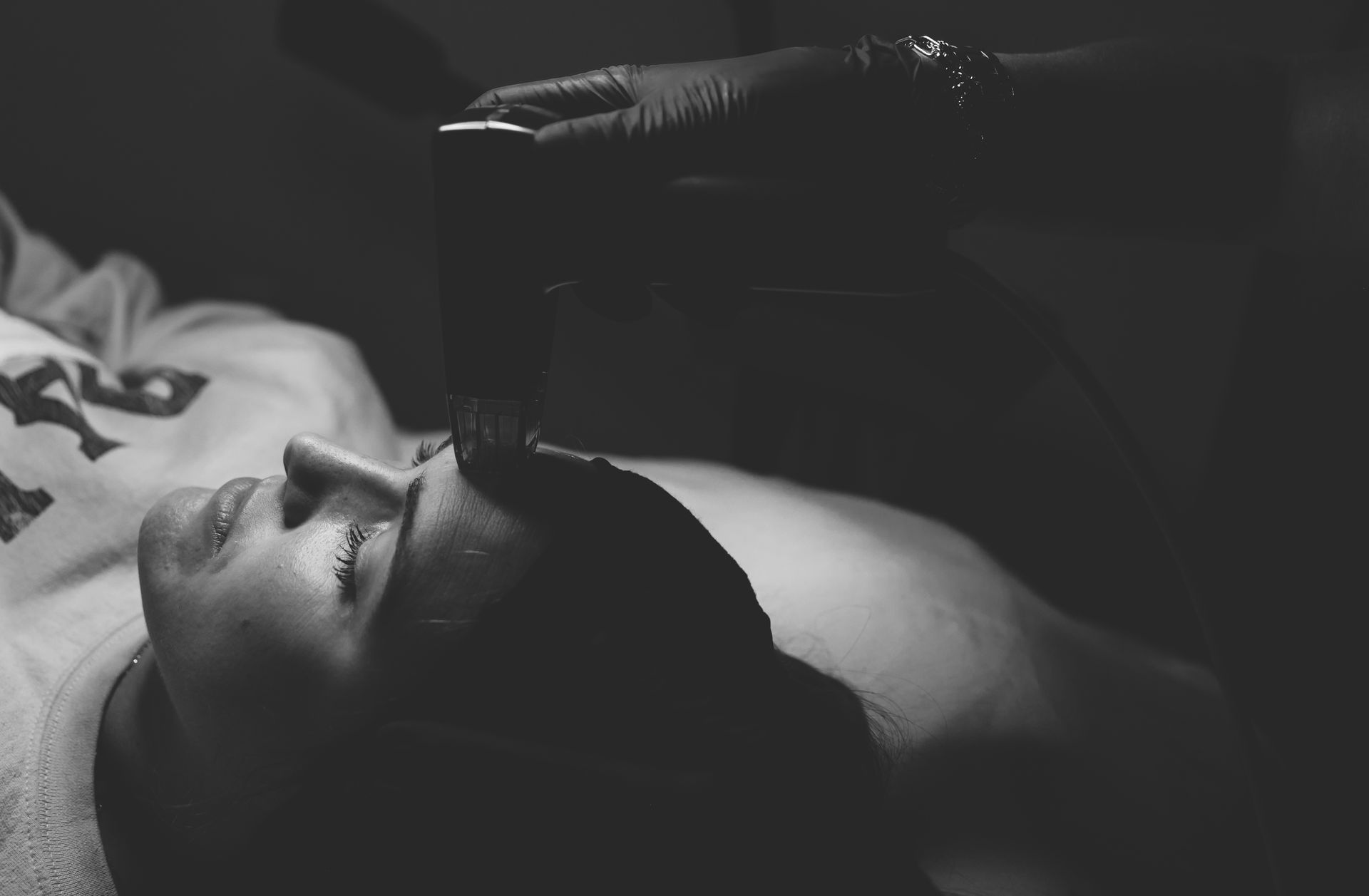 A black and white photo of a woman getting a facial treatment.