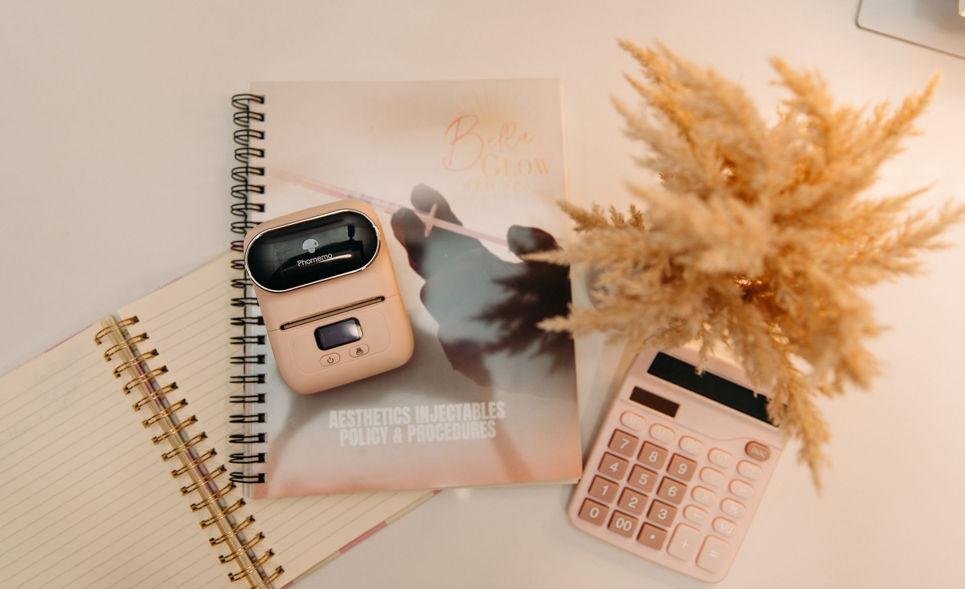 A pink calculator and a notebook are on a table.