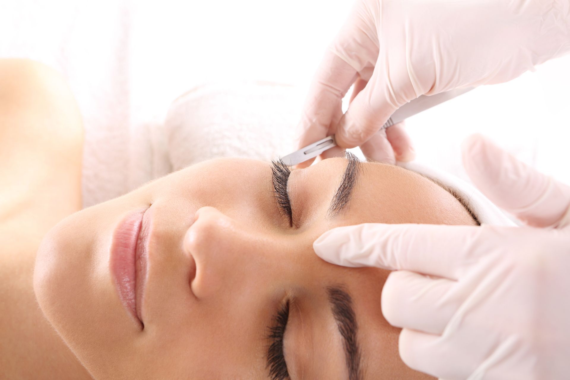 A woman is getting her eyebrows waxed in a beauty salon.