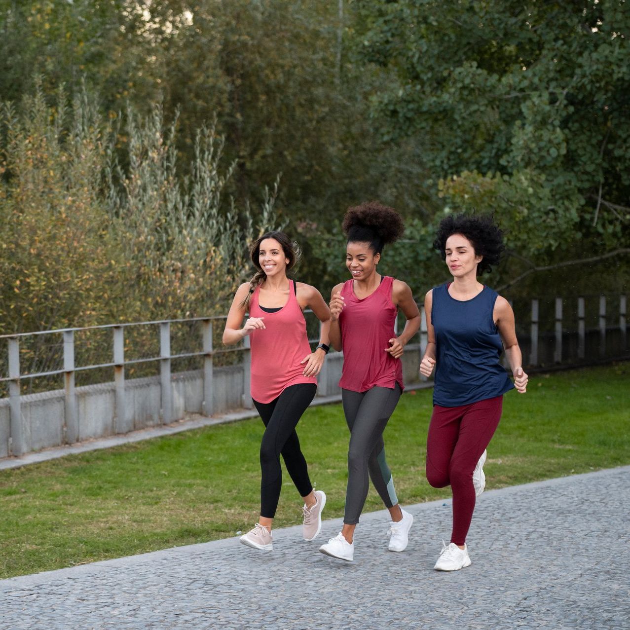 Three women are running on a gravel road.