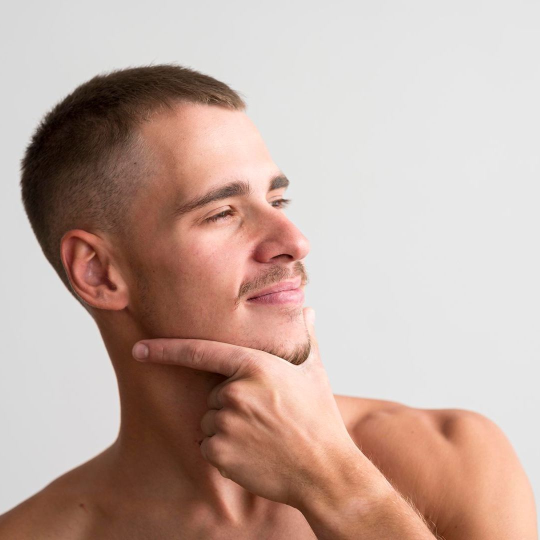 A shirtless man is thinking with his hand on his chin.