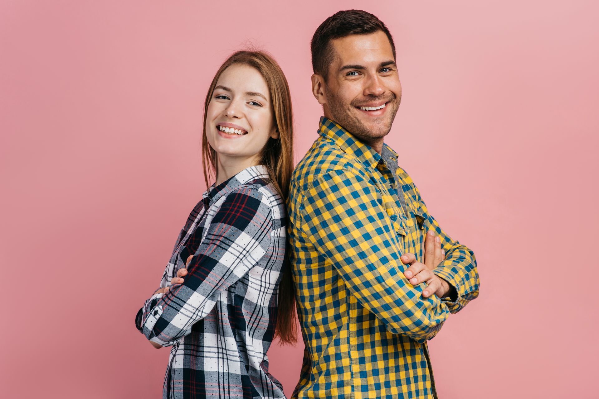 A man and a woman are standing back to back with their arms crossed.