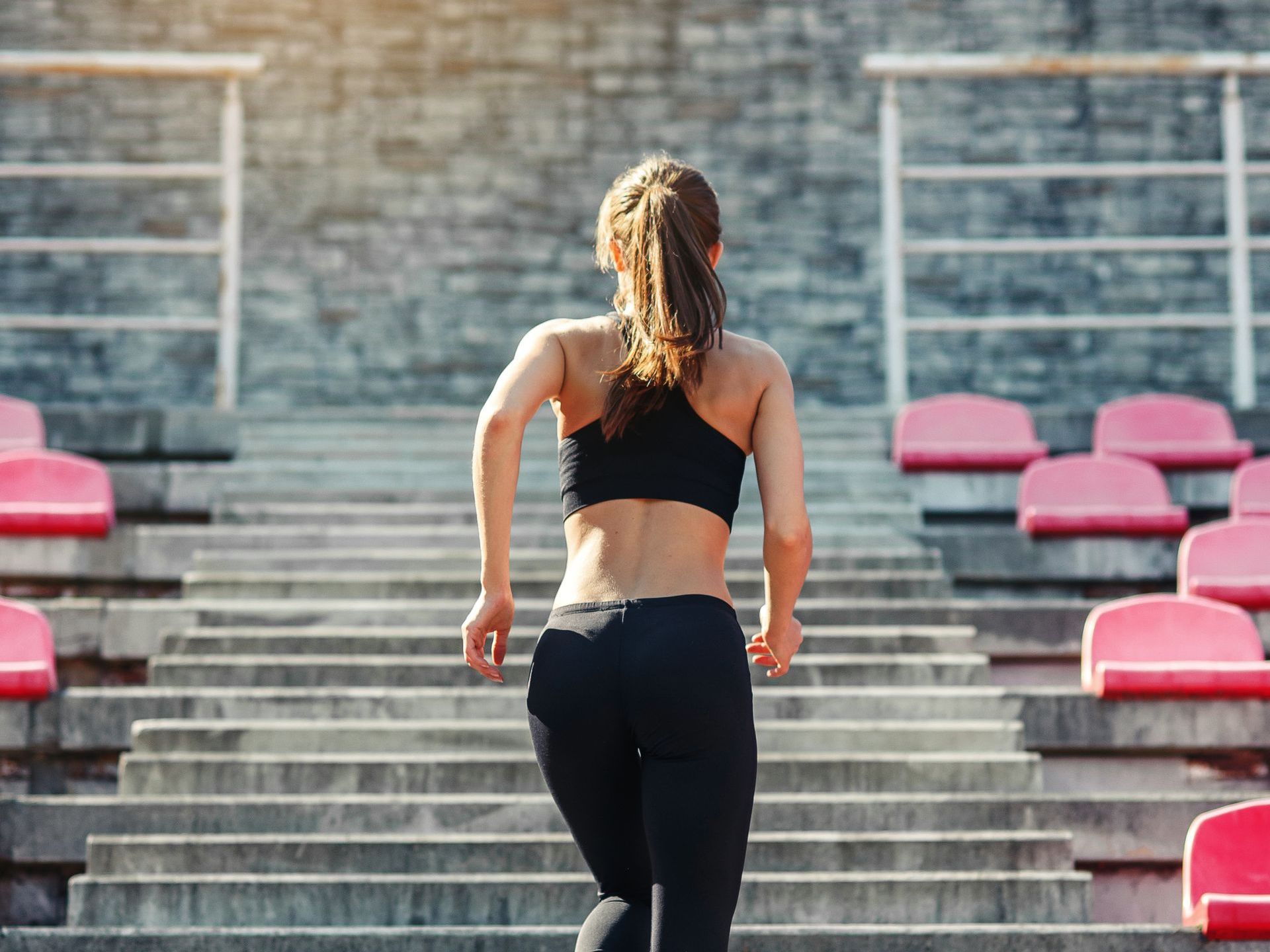 A woman in a pink sports bra and grey sweatpants