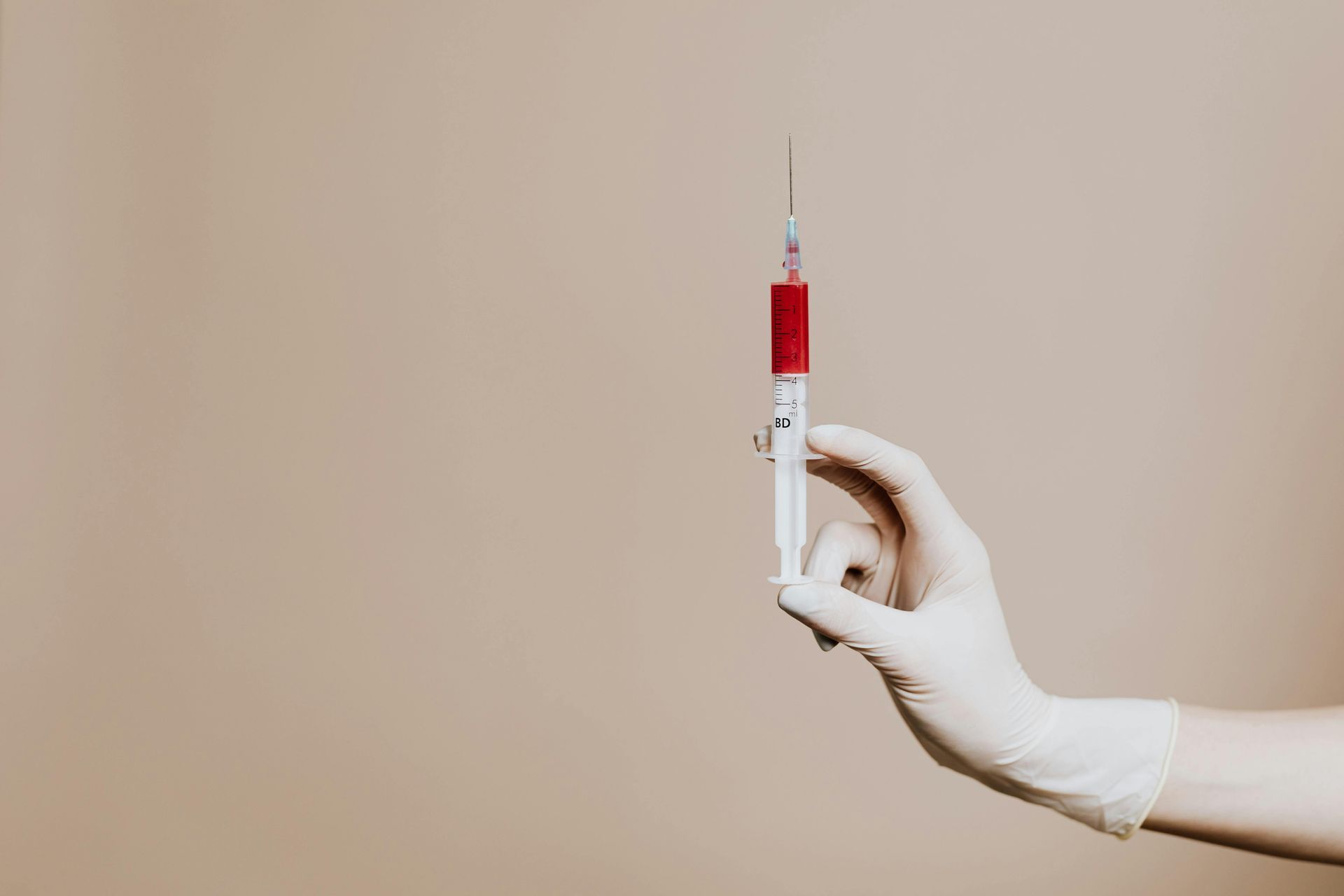 A bottle of b12 vitamins is sitting on a table next to a syringe.