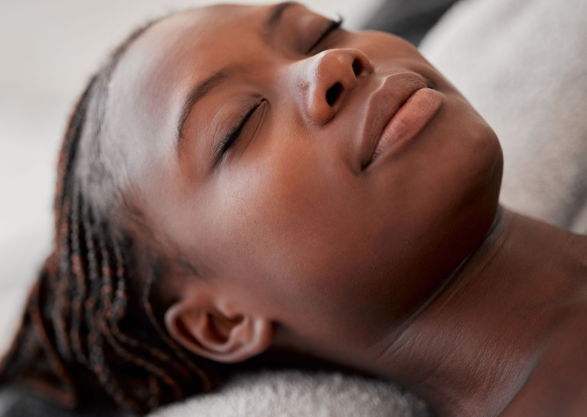 A woman is laying on a towel with her eyes closed.