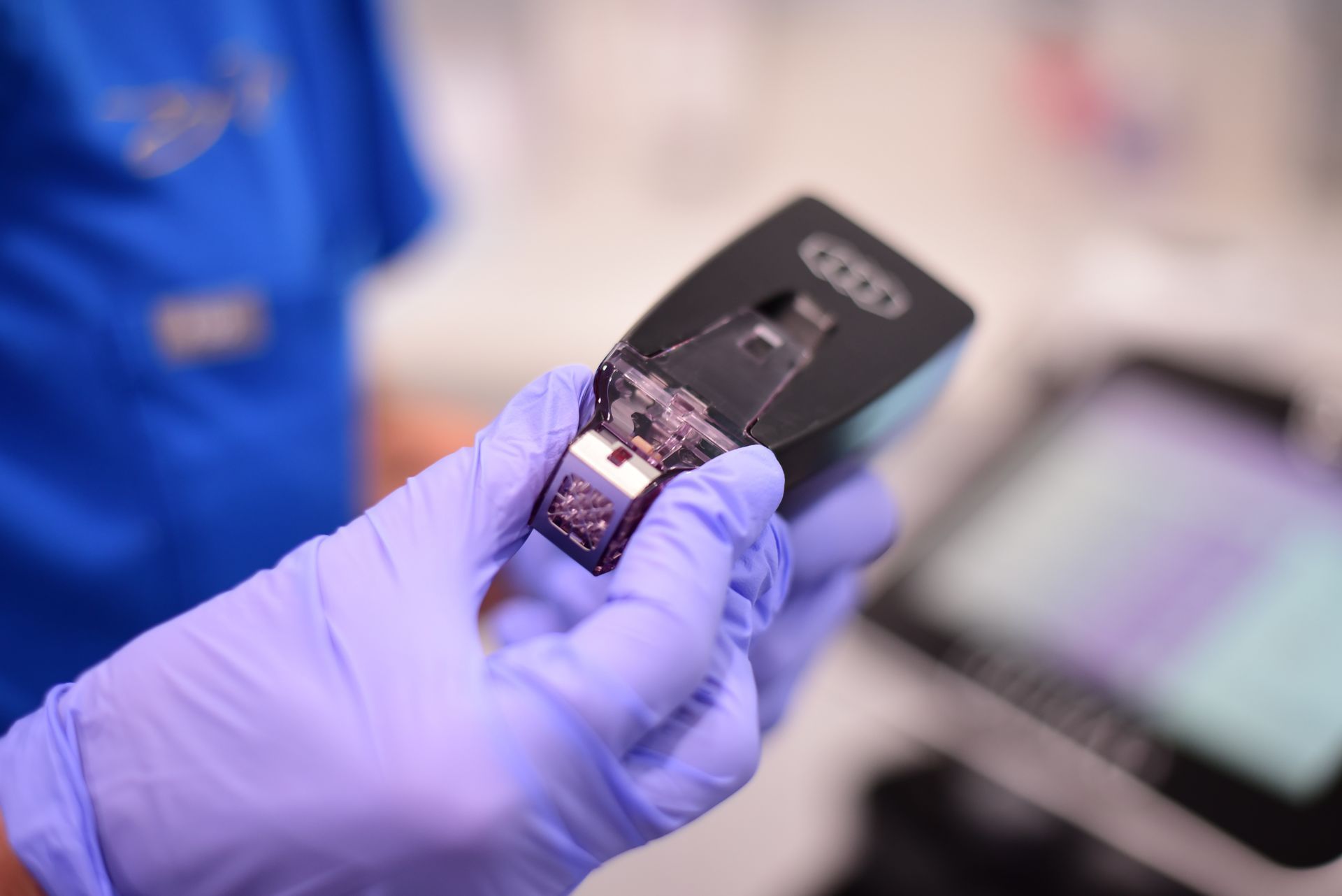 A person wearing purple gloves is holding a cell phone in their hand.