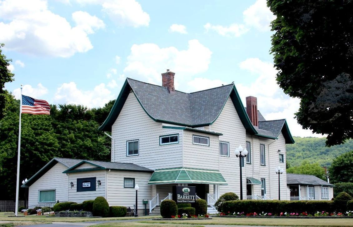 White house with green trim, American flag, blue sky.