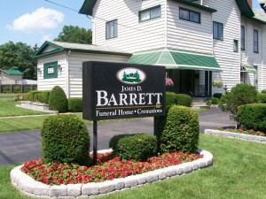 Sign for Jones D. Barrett Funeral Home with building in background. Sign is black with white lettering.