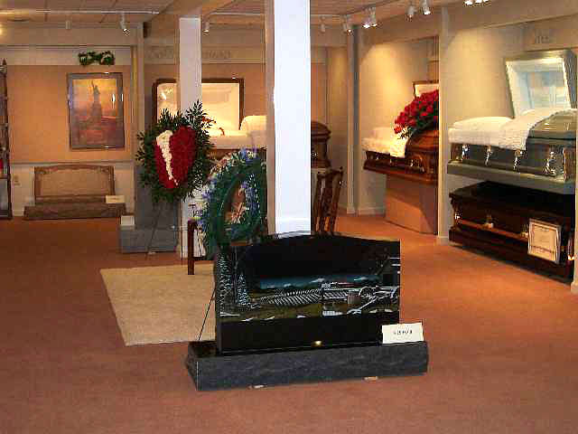 Funeral home interior with caskets on display; wreaths and decorative items on display.