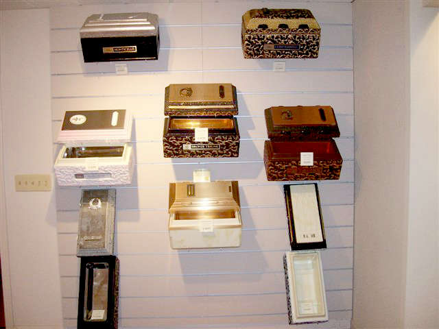 Wall display of various boxes, including vintage, patterned, and solid colored, mounted horizontally.