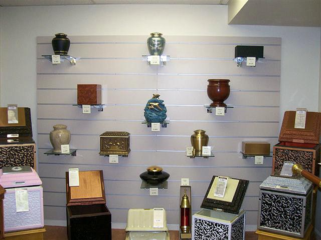 Display of cremation urns in a funeral home, showcasing various shapes, colors, and styles.