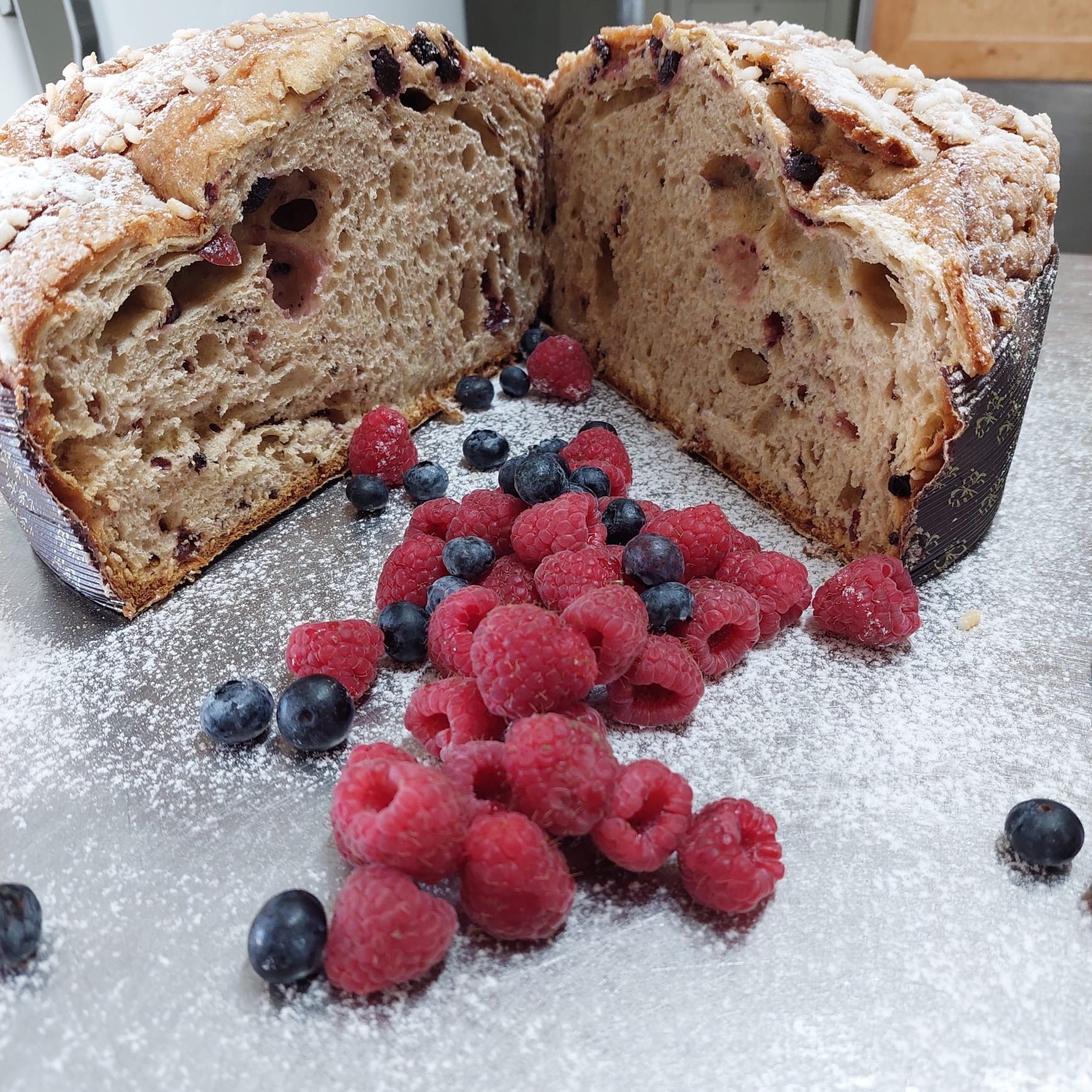 Pane ai frutti di bosco tagliato a fette con lamponi freschi, mirtilli e zucchero a velo.