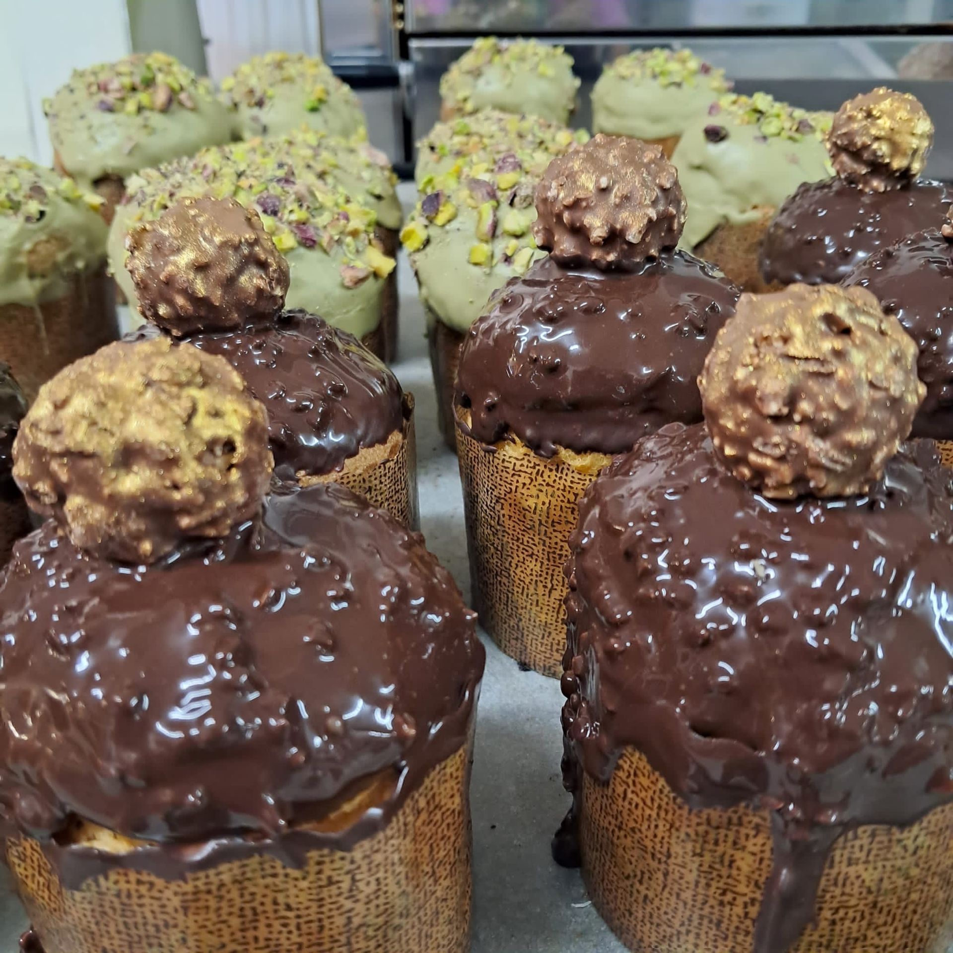 Torte con guarnizioni di cioccolato e pistacchio, alcune con una pallina di cioccolato sopra.