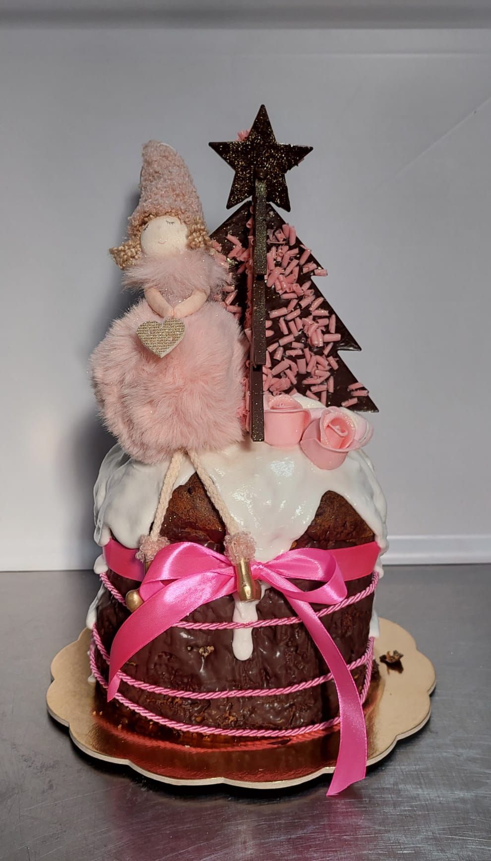 Torta pasquale al cioccolato con dettagli rosa, uno gnomo e decorazioni in cioccolato.