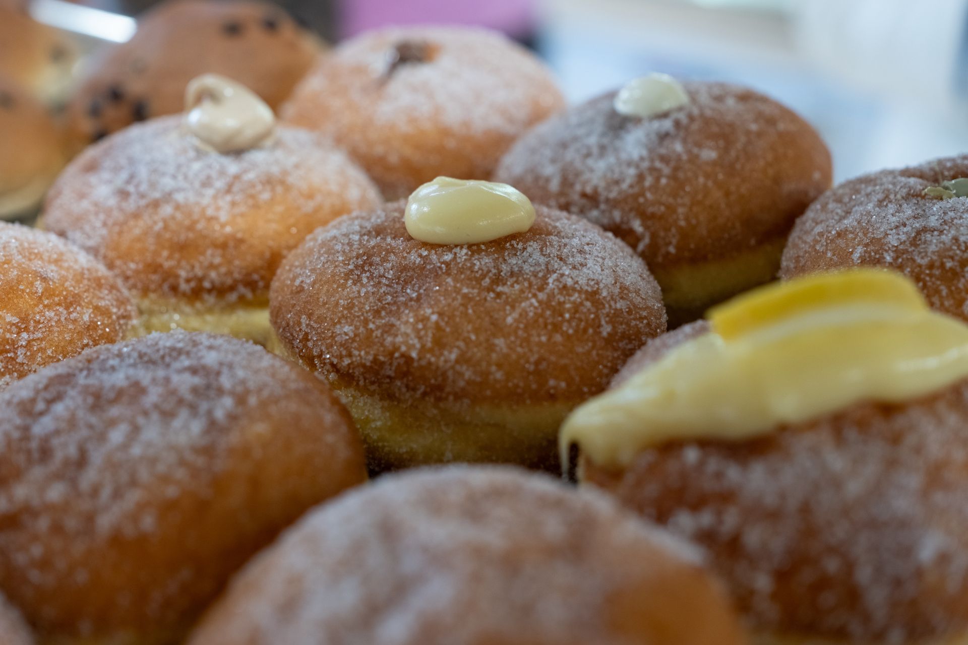 Primo piano di ciambelle zuccherate e ripiene, ricoperte da una crema gialla.