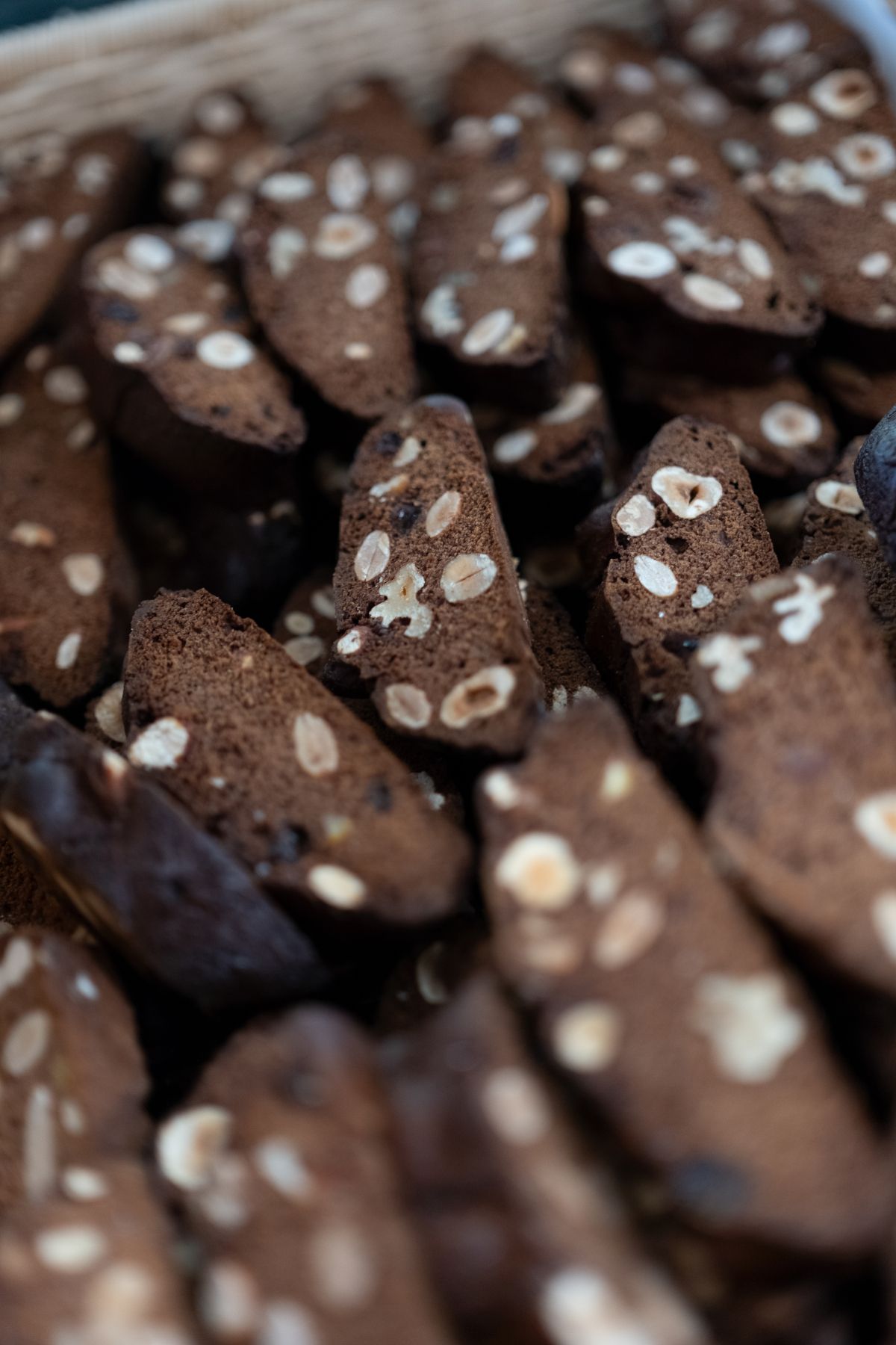 Primo piano di una pila di biscotti scuri, simili a biscotti, tempestati di nocciole.