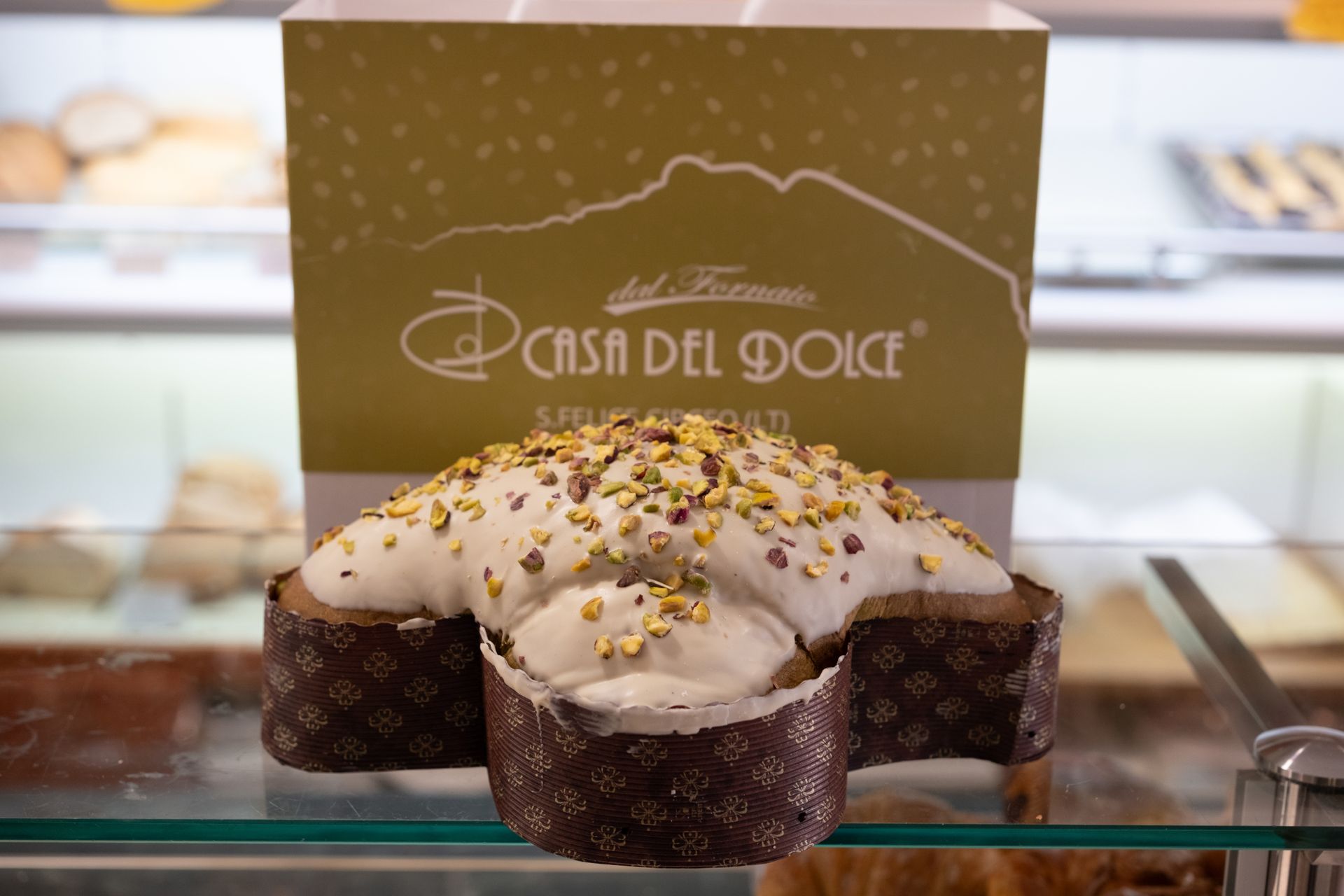 Colomba con glassa bianca e pistacchi, davanti alla scatola 