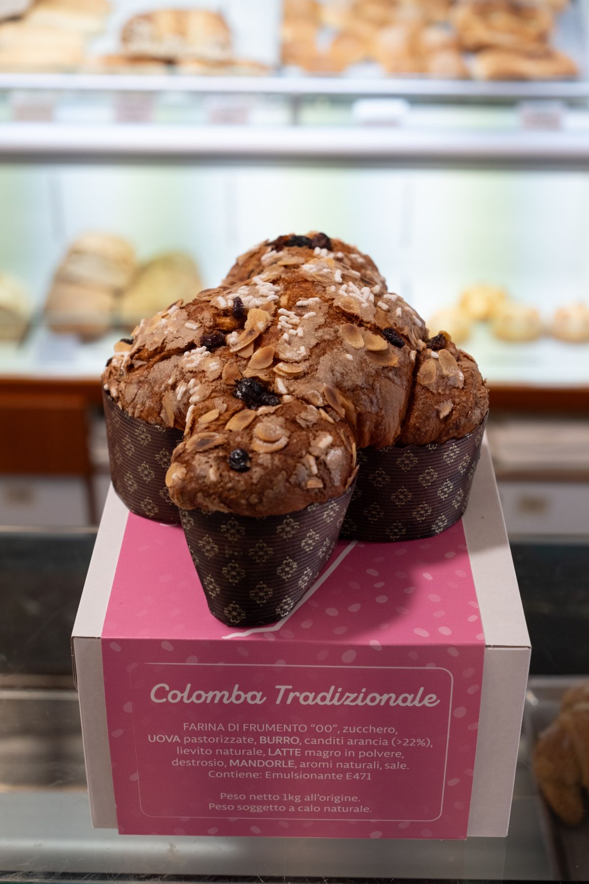 Una colomba in una scatola rosa sul bancone di una pasticceria. È un dolce pasquale italiano a forma di colomba.