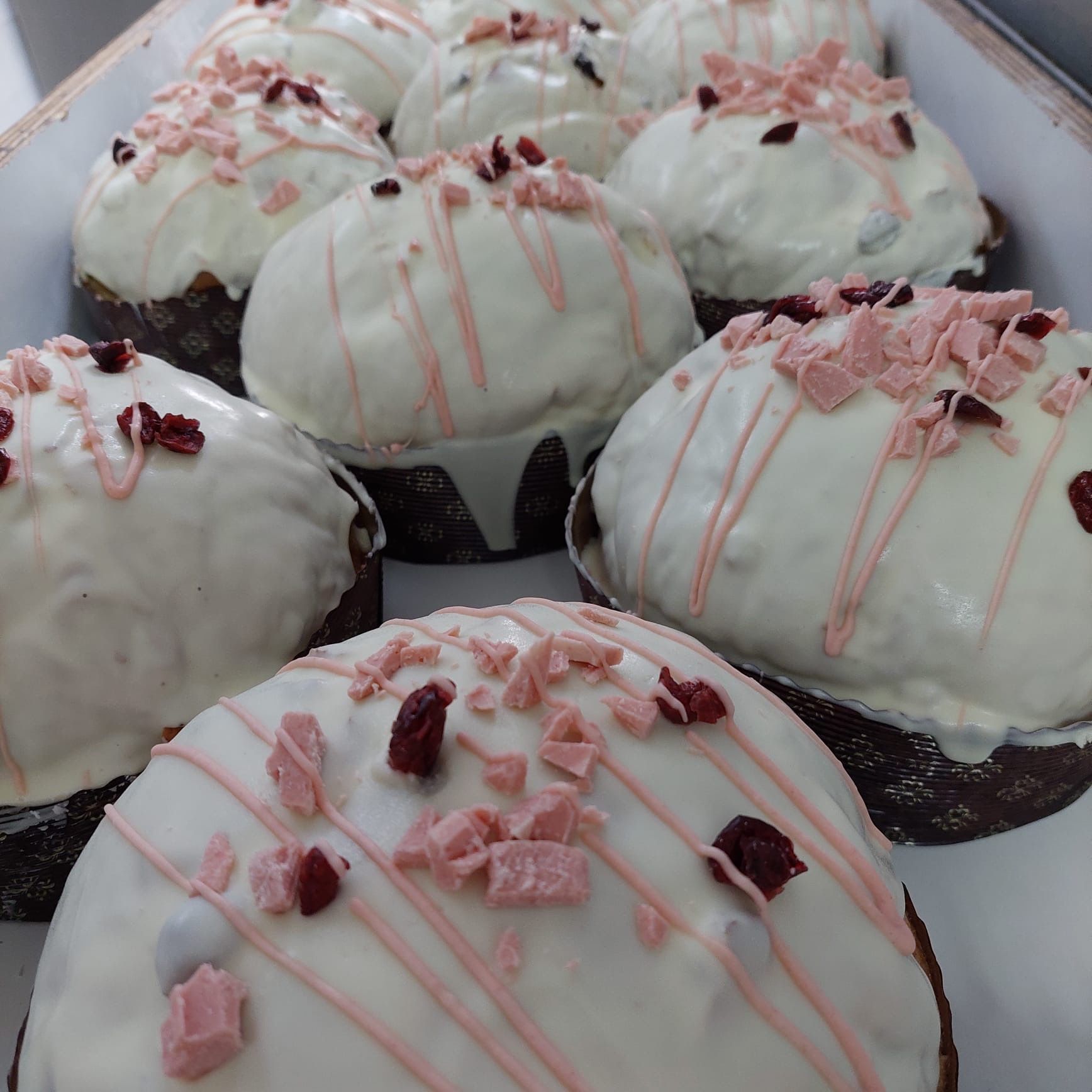 Primo piano di prodotti da forno glassati e ricoperti di mirtilli rossi in una teglia; glassa bianca.