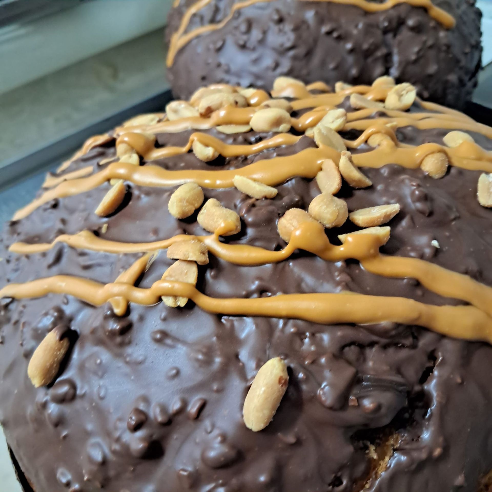 Torta glassata al cioccolato, ricoperta di burro di arachidi e guarnita con arachidi.