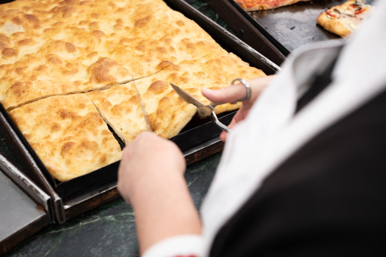 Persona che taglia la focaccia con le forbici.