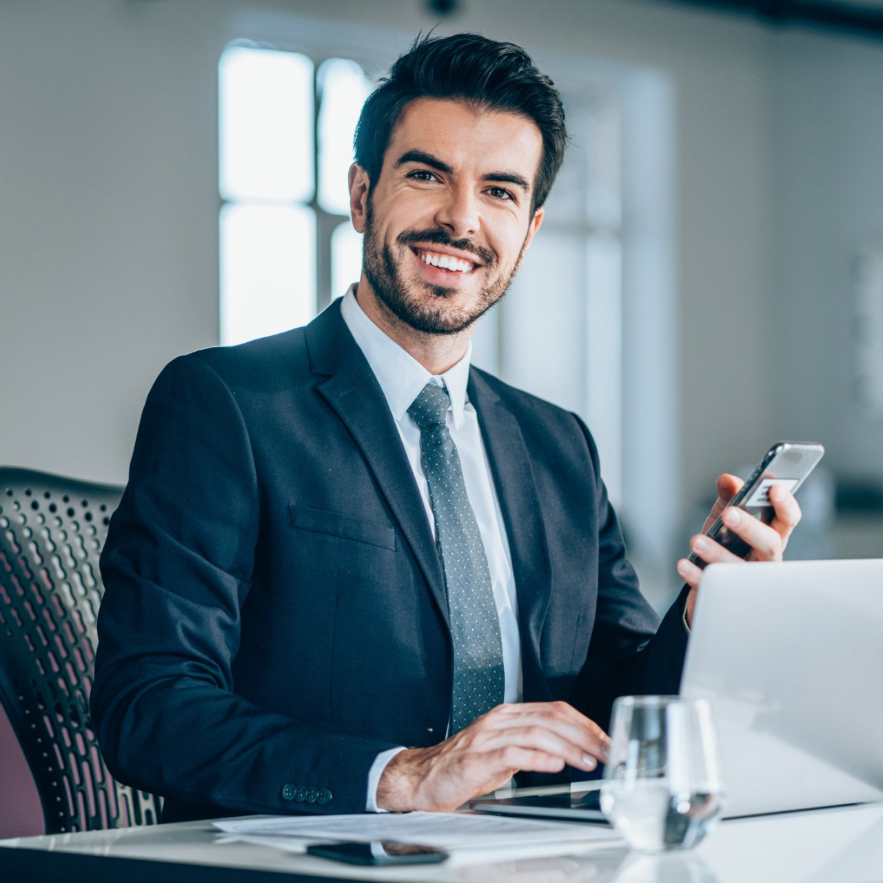 Man In Suite Holding Phone And Smiling