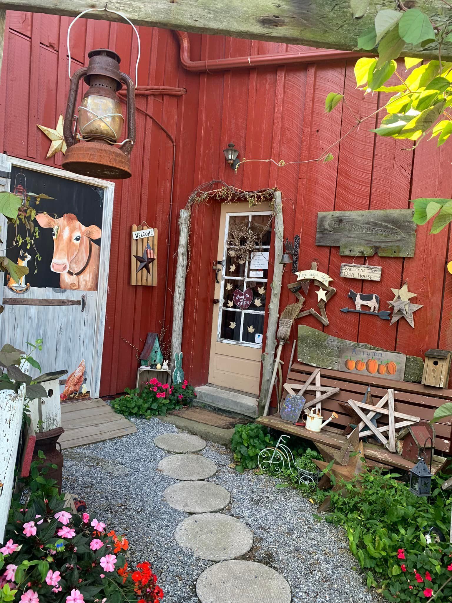 A red barn with a cow painting on the door and a bench in front of it.