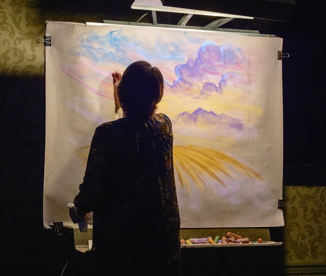 A woman is painting on a large piece of paper