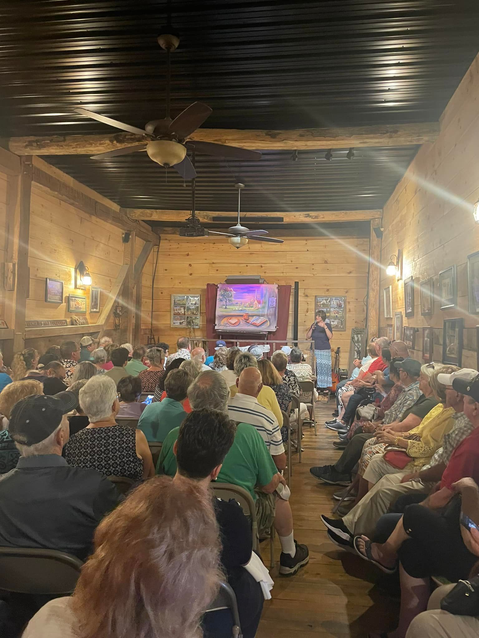 A large group of people are sitting in a room watching a presentation.