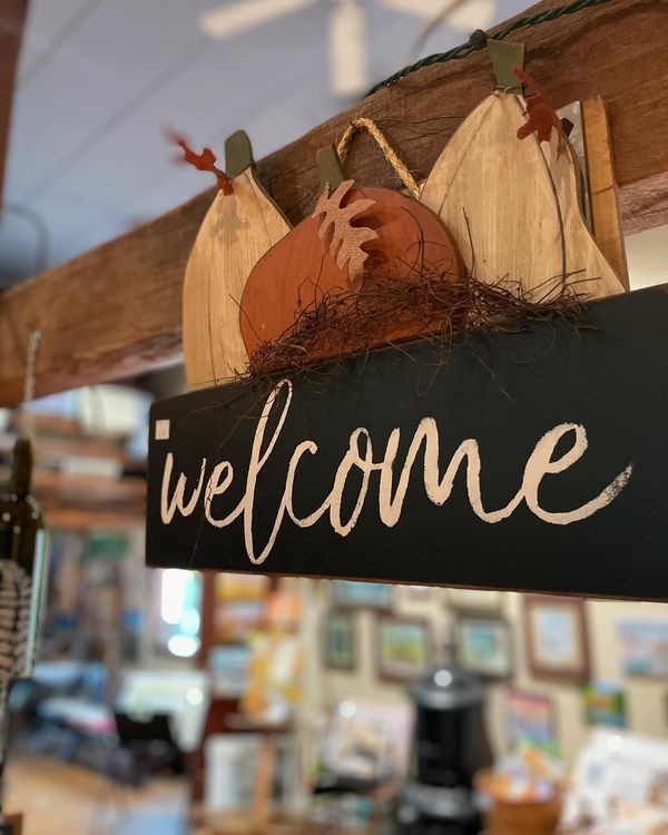 A welcome sign with a pumpkin on top of it