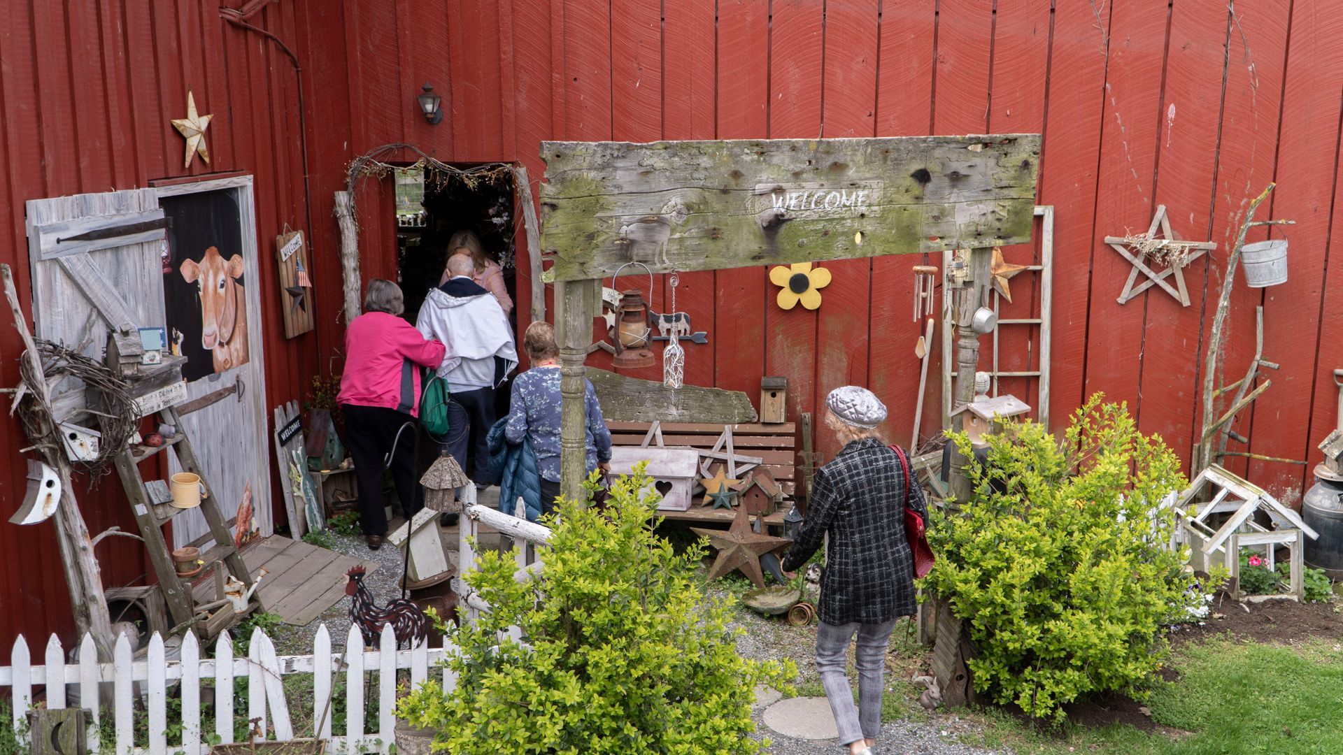 A group of people are standing in front of a red barn.