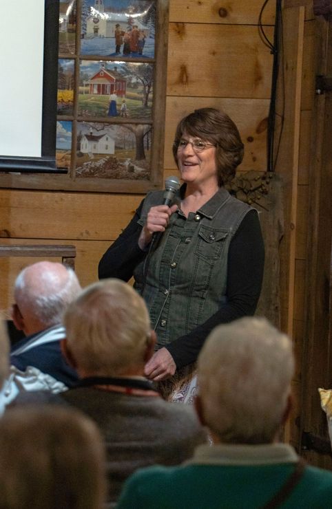 A woman is speaking into a microphone in front of a group of people.