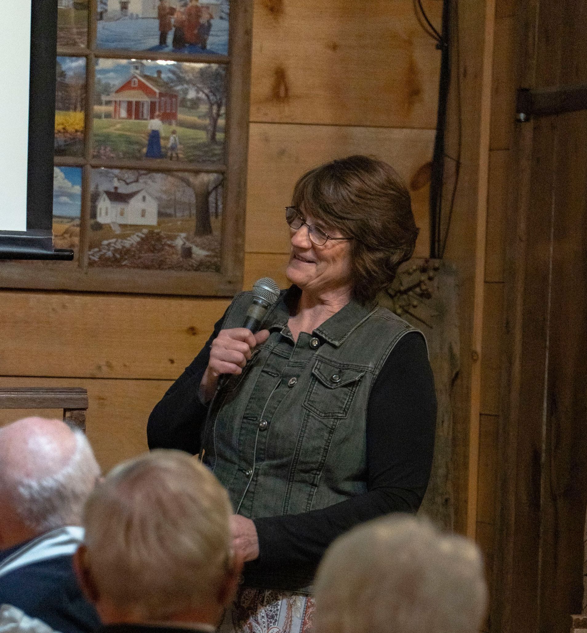 A woman is holding a microphone in front of a group of people.