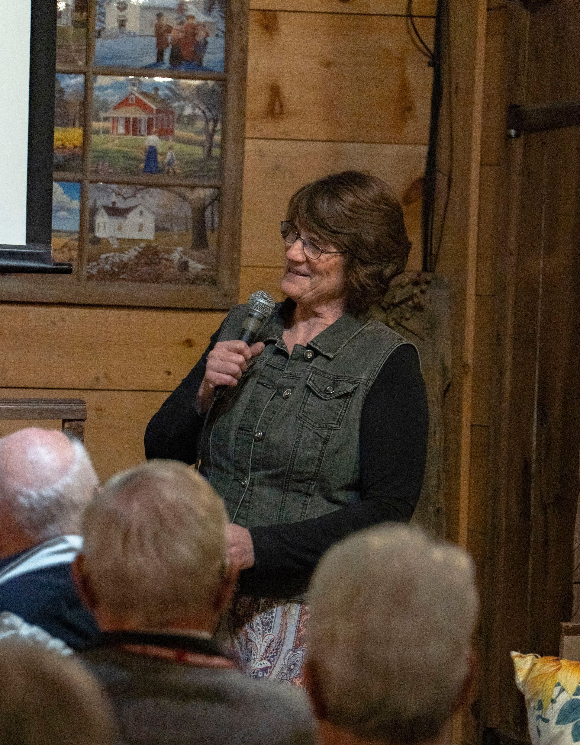 A woman is speaking into a microphone in front of a group of people.