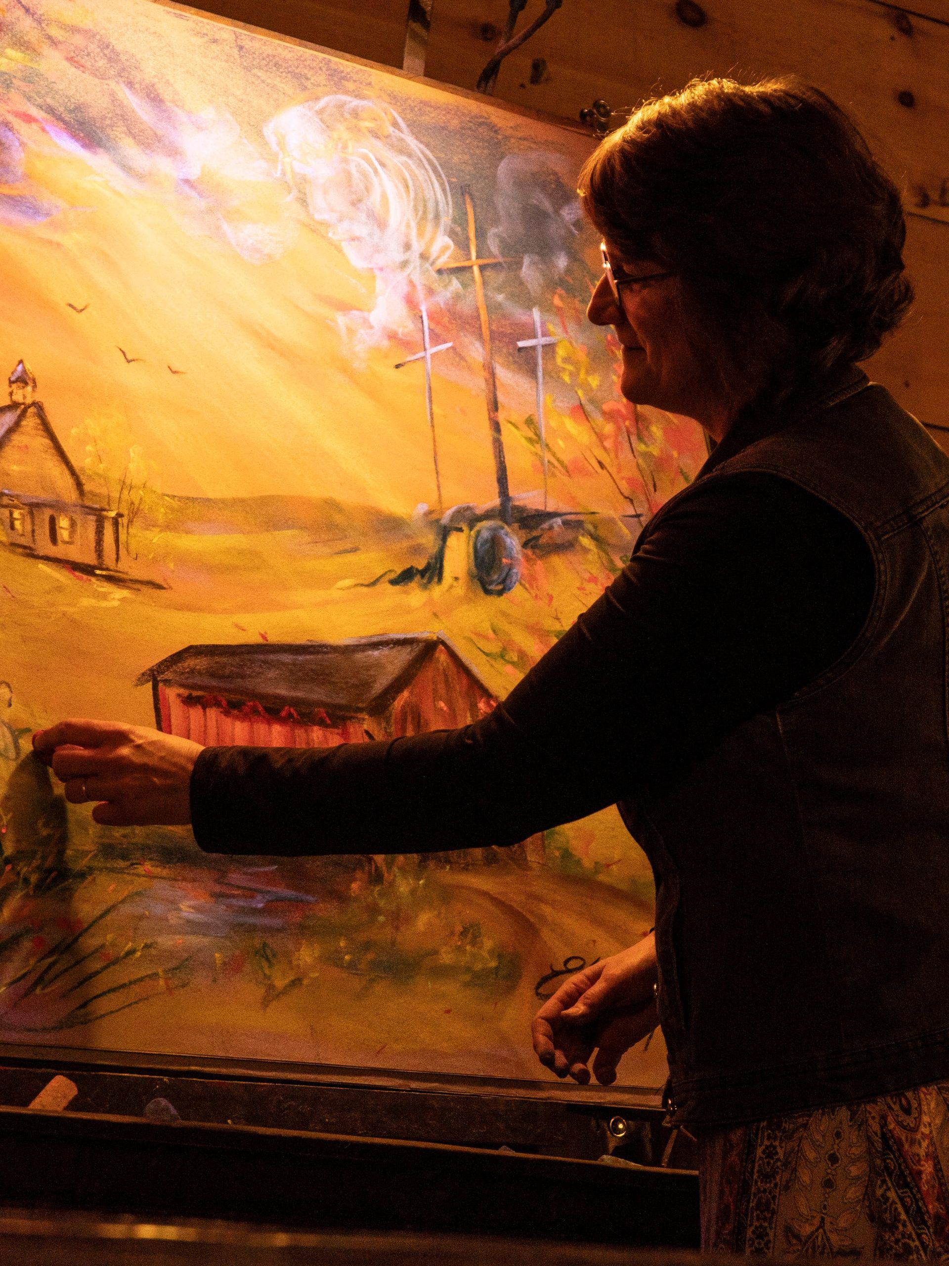 A woman is painting a picture on a large canvas.