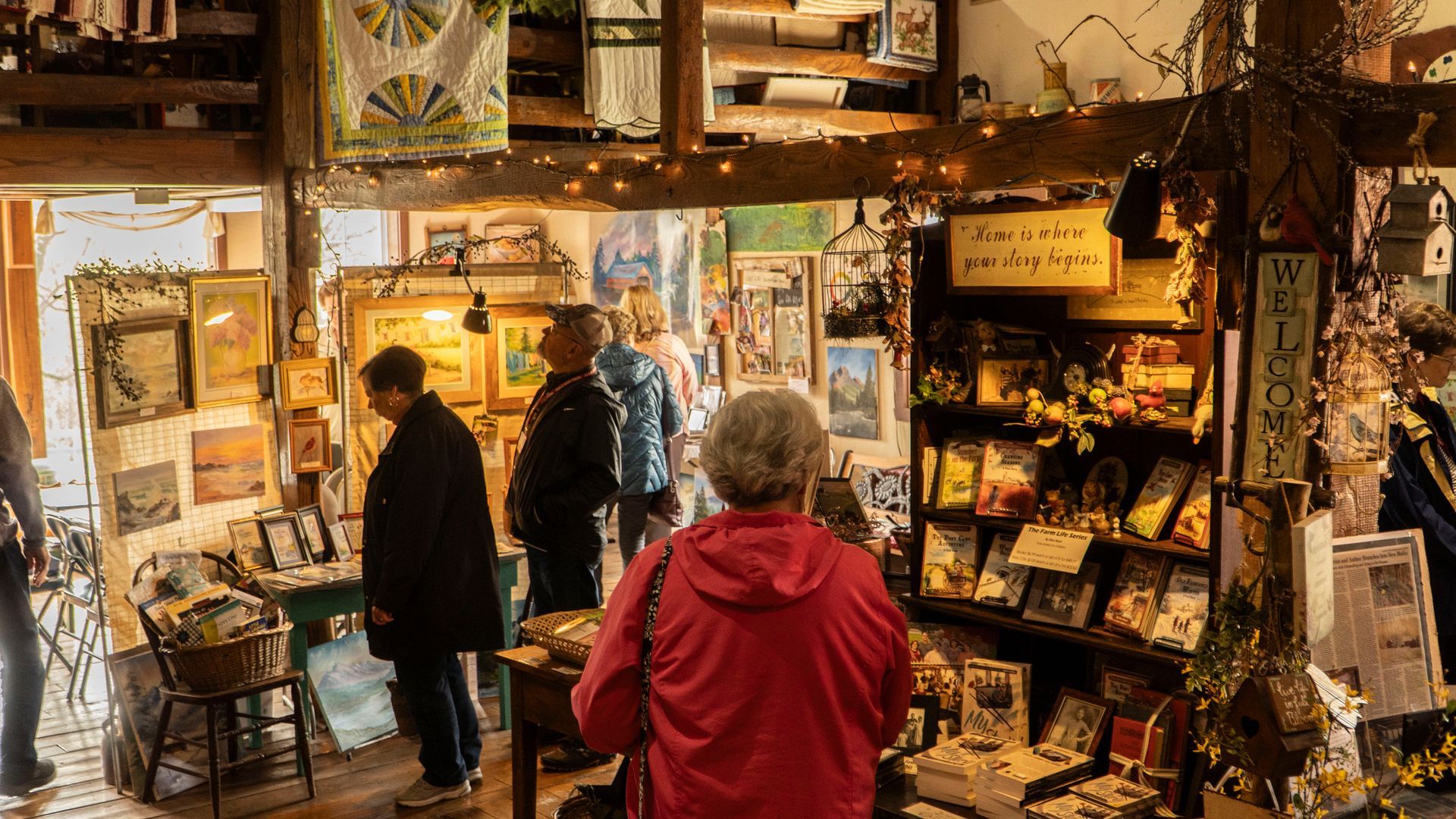 A woman in a red jacket is standing in a store looking at books.