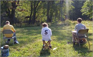 A girl with the number 5 on her back sits in the grass