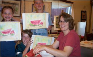 A woman and three children are holding up watermelon paintings