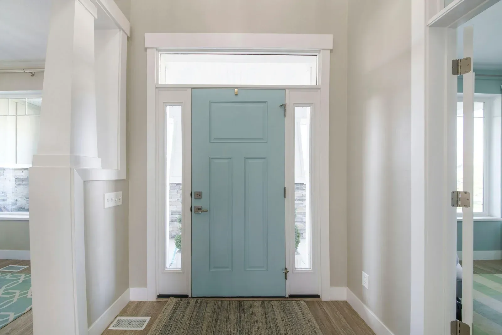 Light blue front door in a bright entryway with white trim and patterned rug