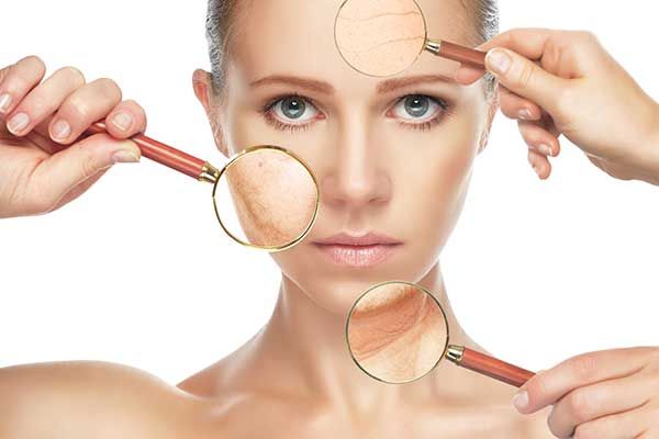 A Woman is Looking at Her Face Through Magnifying Glasses — Renew Laser Clinic in Taree, NSW