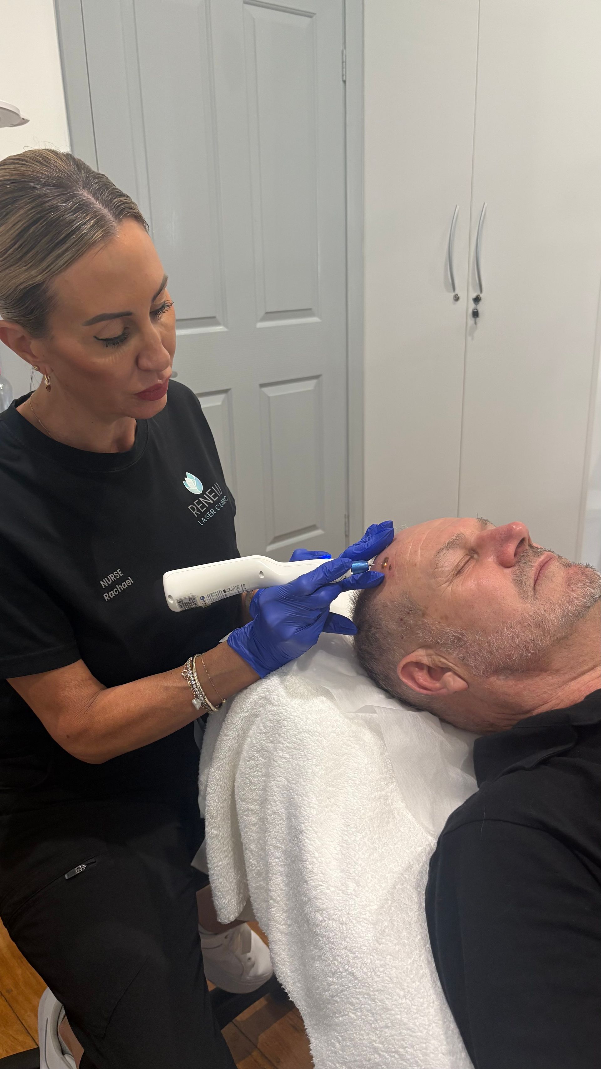 A Woman Is Applying A Cream To A Man 's Head — Renew Laser Clinic in Taree, NSW